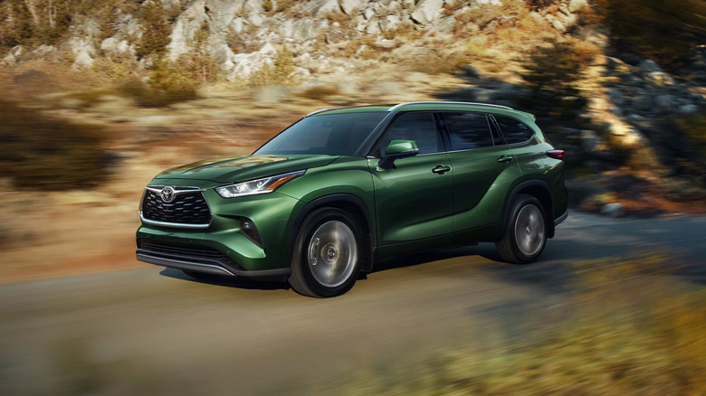 A green Toyota Highlander on a country road