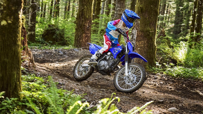 Teen riding blue 2026 TT-R 125 LE in the woods