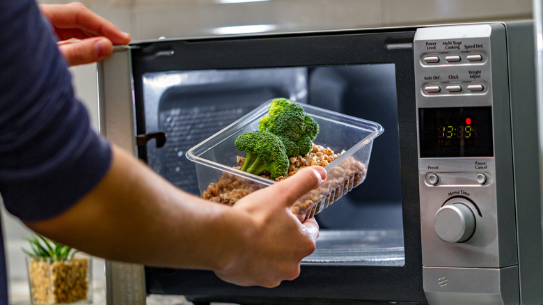male putting food inside microwave