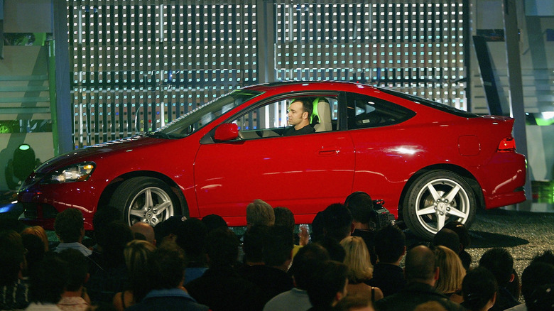 A red Acura RSX on stage at a car show