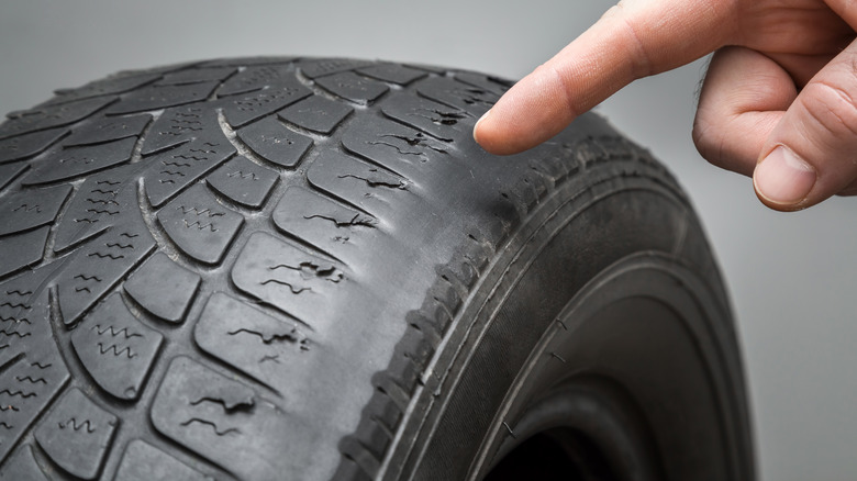 Finger pointing to worn out tire treads 