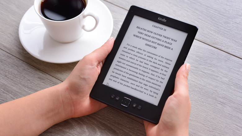 Hands holding 4th generation Amazon Kindle on a desk