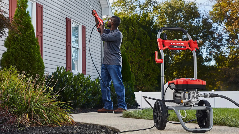 A man using a Craftsman pressure washer to clean his siding