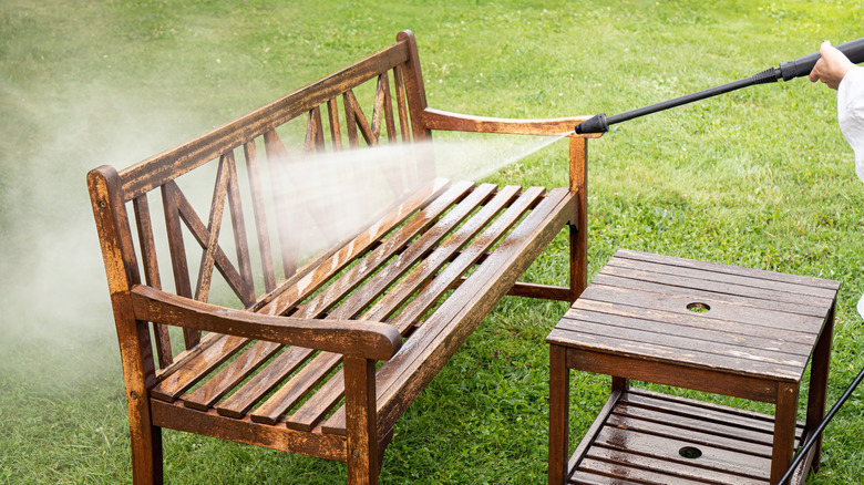 Close-up of a person pressure washing wood patio furniture