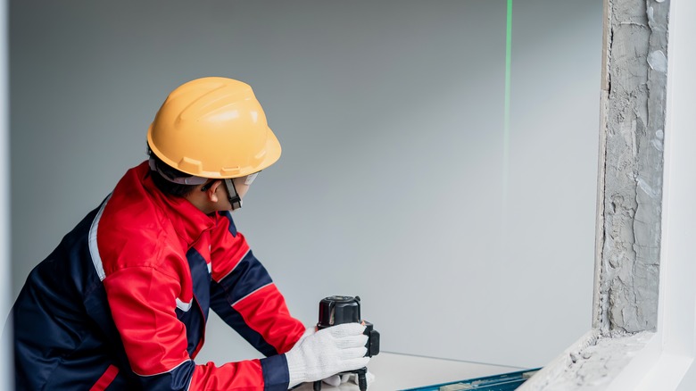 A construction worker uses a laser level