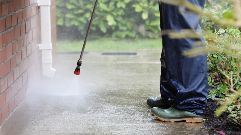 Person cleaning garden path with pressure washer 