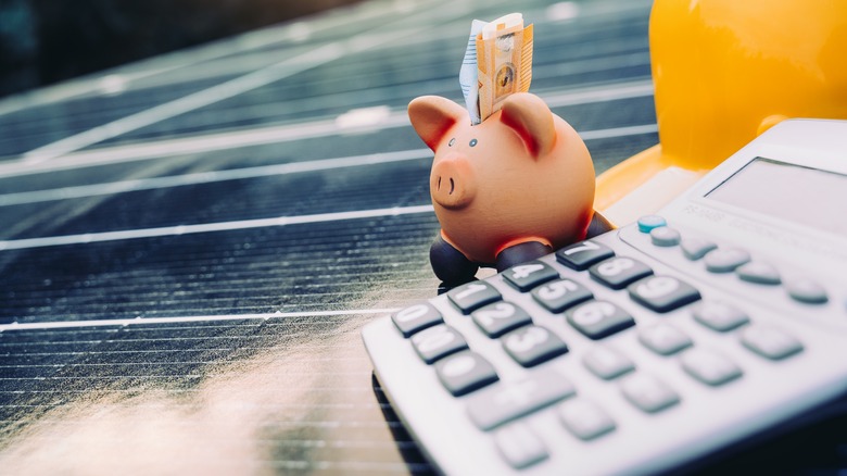 Piggybank and calculator on a solar panel