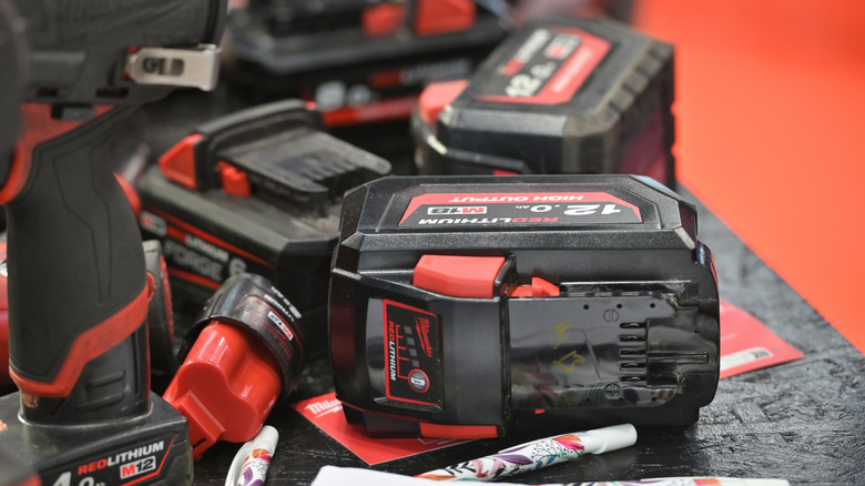 Several Milwaukee batteries laying on table next to tools