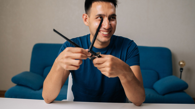 Portrait of smiling technician male assembling wi-fi module by connecting antennas