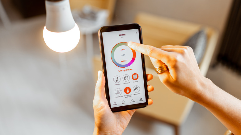 Woman using a smartphone to adjust the settings on a smart bulb