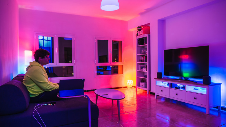 Man sitting on couch in room with colored smart lights