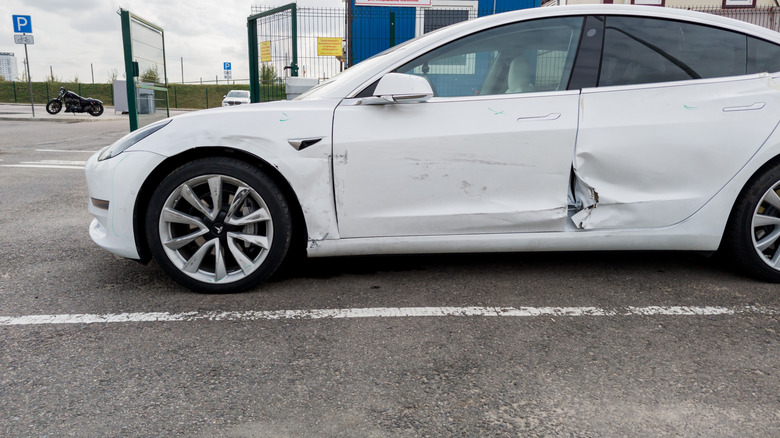 Side-on view of a white Tesla Model Y with crash damage