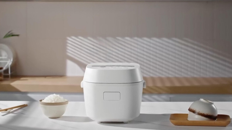 Toshiba Rice Cooker on white table with bowl of rice and chopsticks
