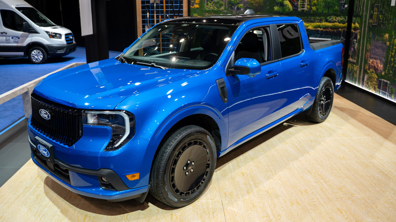 Front three-quarters view of a blue 2026 Ford Maverick Lobo pickup on display at auto show.