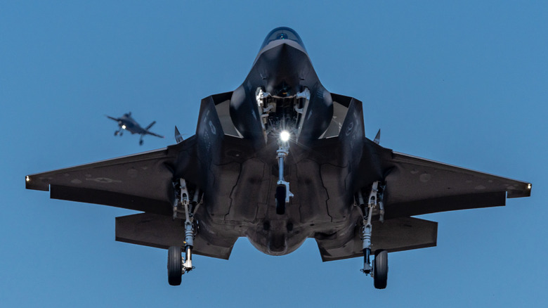 An F-35A Lightning II in the air against a blue sky with its landing gear out