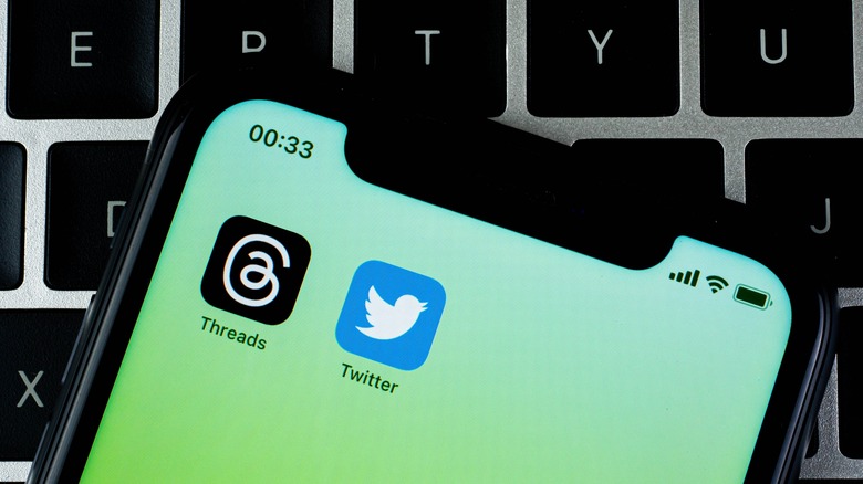 Tópicos e aplicativos do Twitter em um iPhone colocados no teclado do MacBook
