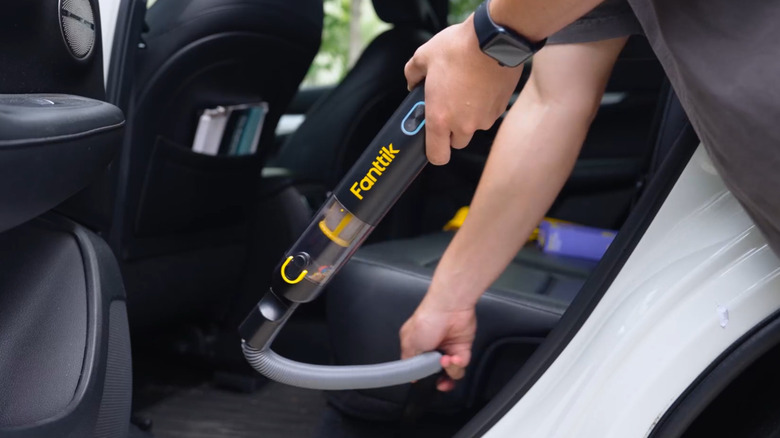 Person using the Fanttik Slim V8 APEX Car Vacuum to clean the backset of their vehicle.