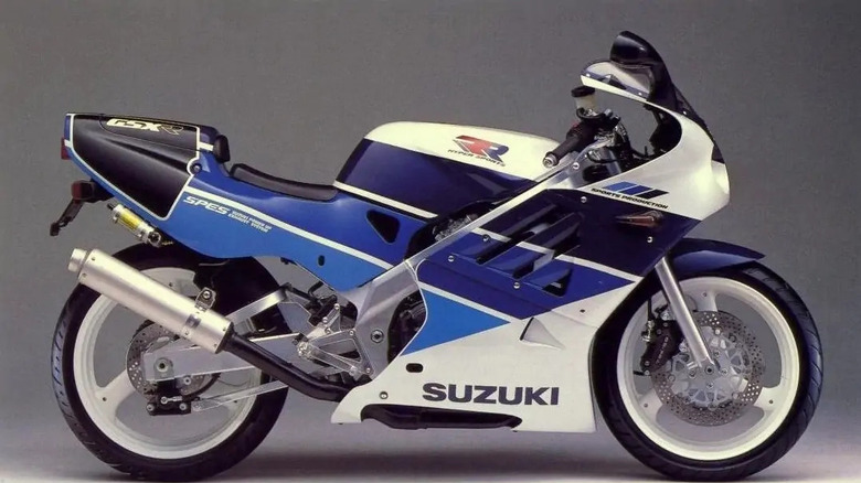Side view of a 1989 Suzuki GSX-R250R SP in blue and white racing livery, featuring aerodynamic fairings, a single seat, and "SP" and "Sports Production" decals on the tail and fairing.