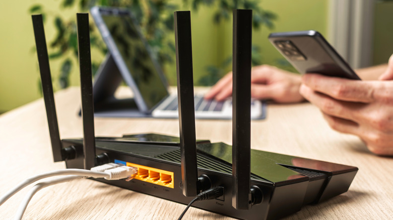 Wireless internet router on light office desk with phone and laptop in background