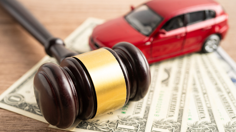 Judge's gavel and red model car on top of U.S. bank notes