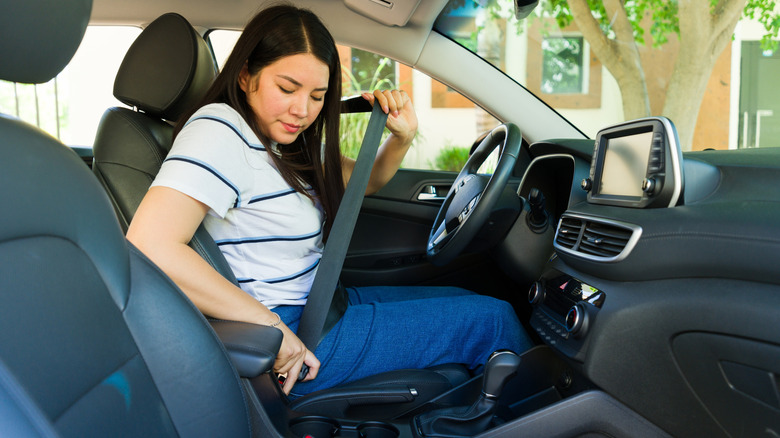 Mexican woman putting on the seat belt before driving the car