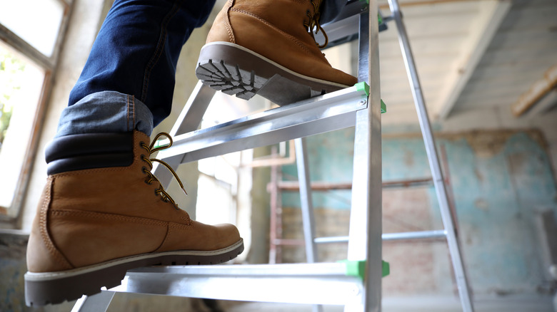 Close-up of a man's feet in work boots on a metal ladder