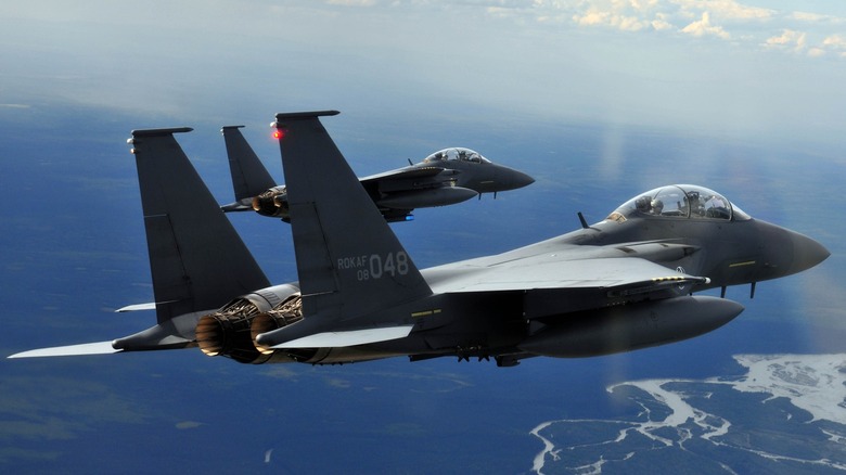 Two A ROKAF F-15K Slam Eagles flying in formation, rear 3/4 view, clear skies