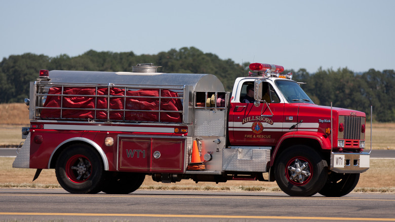 Water truck with fire fighters inside driving down roadway