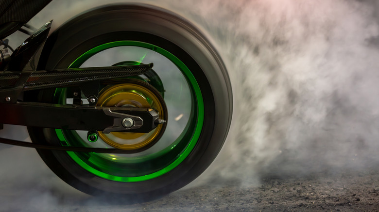 Motorcycle tire burns rubber on the road producing smoke