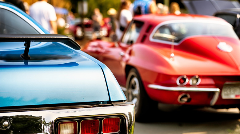 A close-up view of a rear end of two muscle cars.