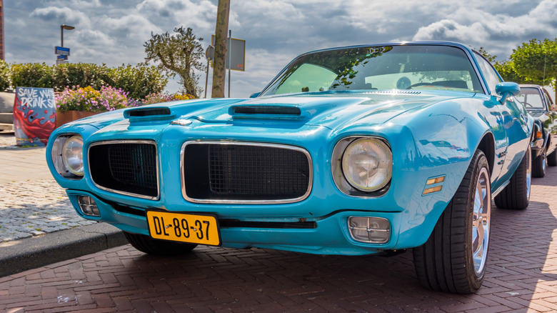 A close-up of a front-end of a parked light blue 1972 Pontiac Firebird.