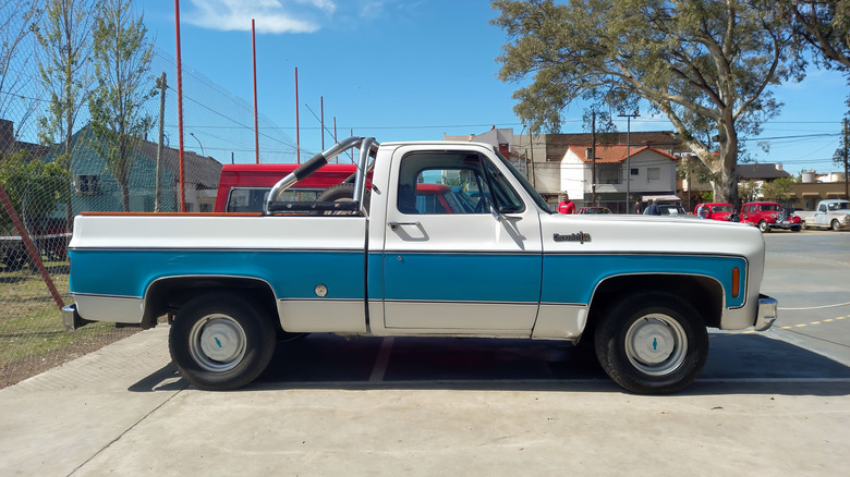 A side profile view of a dual-tone 1970s Chevrolet C10 pickup truck parked outside.