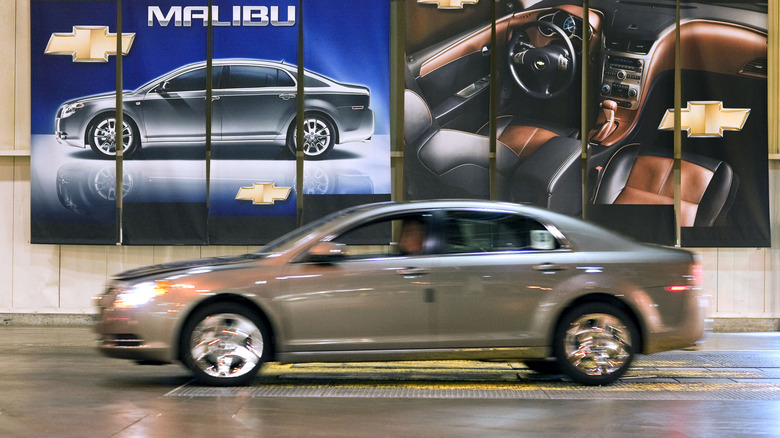 A side profile view of a gray 2010 Chevrolet Malibu blurred in motion.