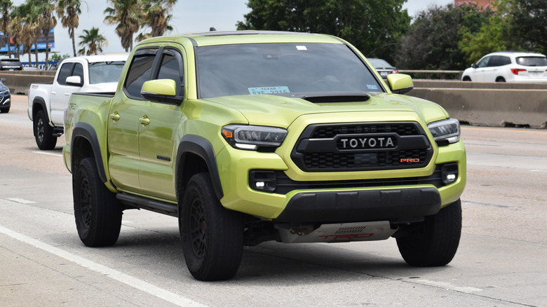 A lime yellow 2018 Toyota Tacoma being driven on a public highway.