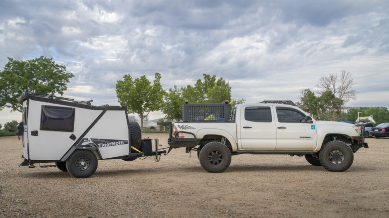 A modified 2009 Toyota Tacoma towing a trailer on gravel.