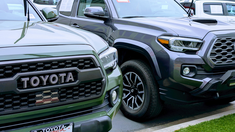 Two Toyota Tacoma trucks in front of a dealership.