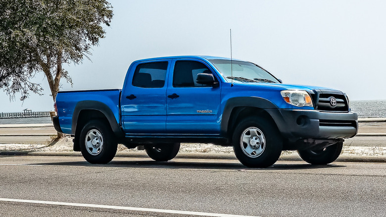 A blue 2006 Toyota Tacoma being driven on a seaside road.