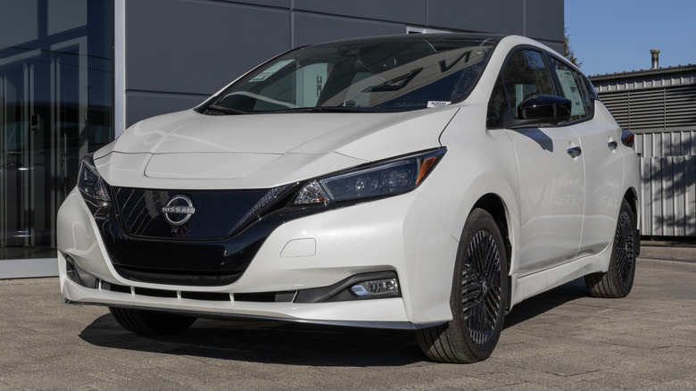 A new white Nissan LEAF EV parked in front of a dealership.