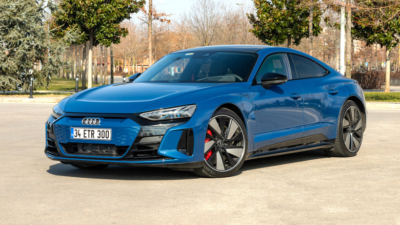 A blue Audi RS e-Tron GT Performance parked outdoors with trees in the background.