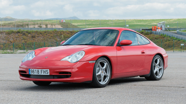 A three-quarter view of a red 996 Porsche 911 parked on a track.