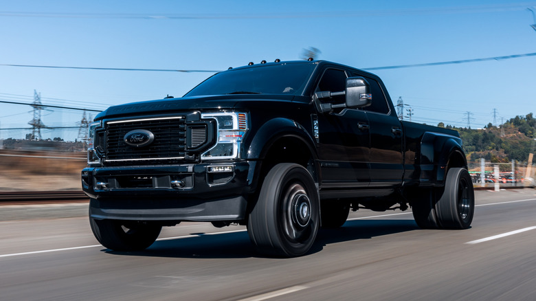 A black Ford F-450 Heavy-Duty duallie truck driving on the road.