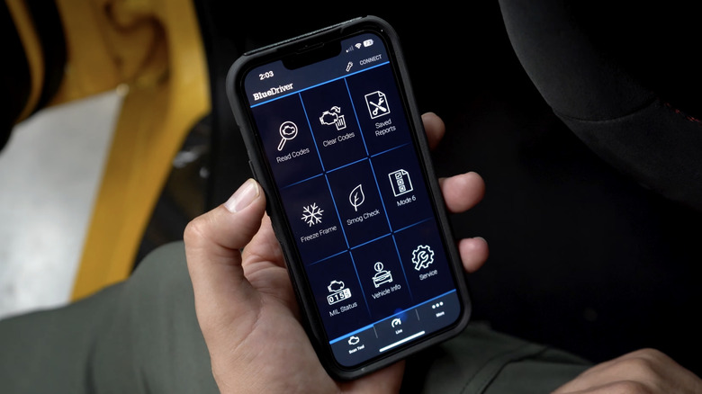 A person holding a smartphone displaying the BlueDriver OBD-II app interface.