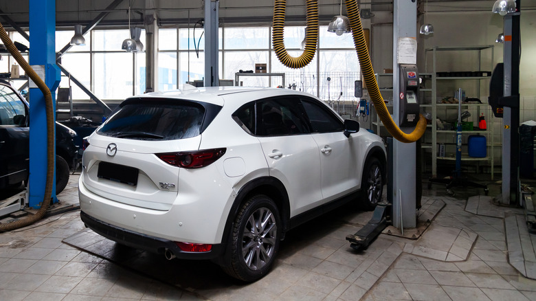 A white Mazda CX-5 parked inside a repair shop.