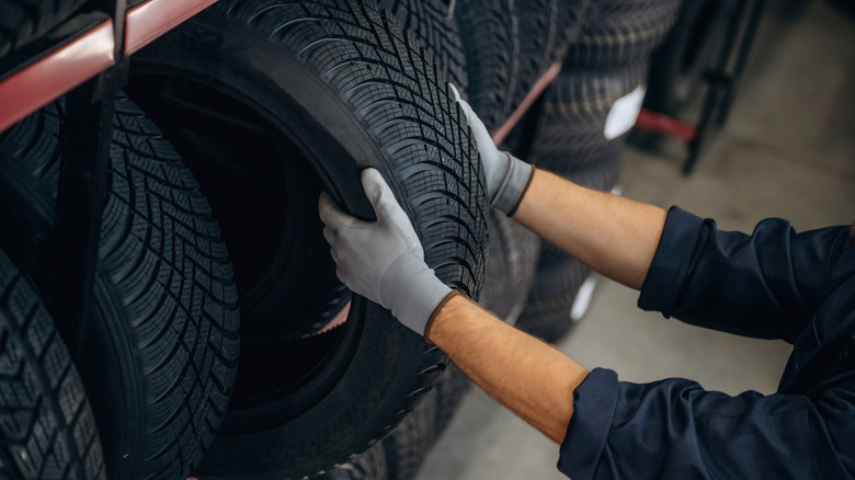A close-up view of a person taking out a tire from a tire rack.