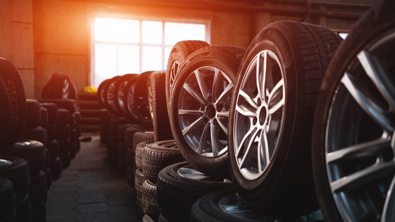 An indoor storage room filled with tires and wheels, with sunrays streaming through the window.