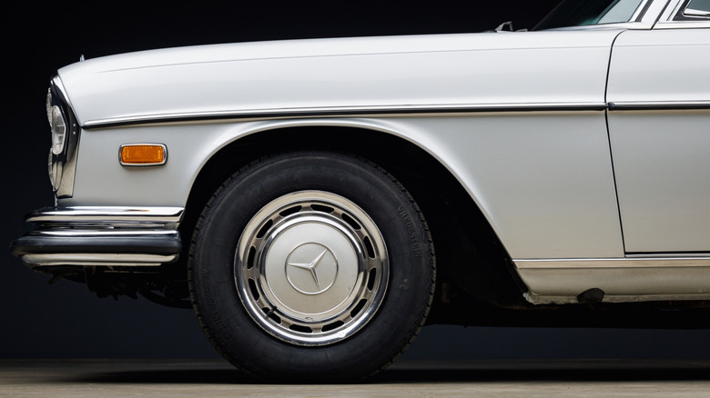 An front-end side close-up of an old white Mercedes wearing white wheels and Vredestein tires.