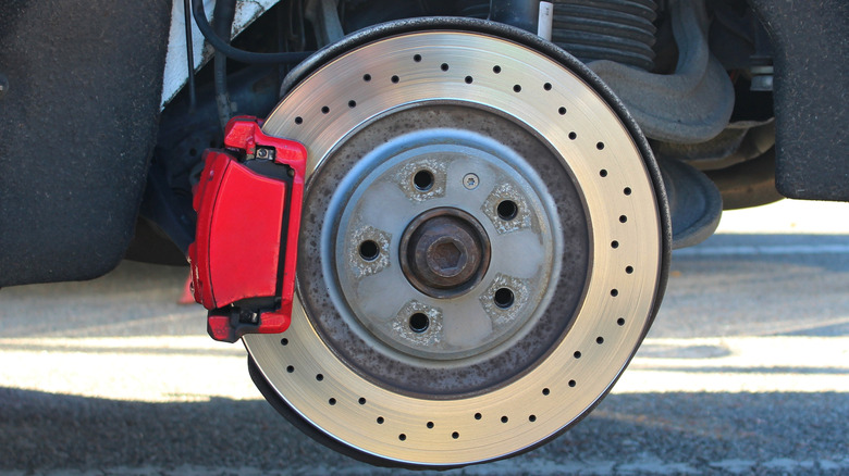 Red floating brake caliper over the rotor attached to a vehicle wheel