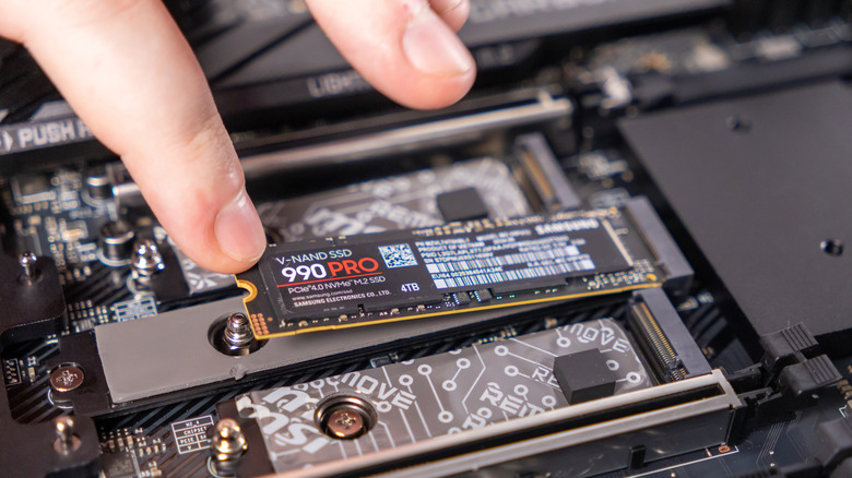 A person installing a Samsung 990 PRO M.2 NVMe SSD on a motherboard
