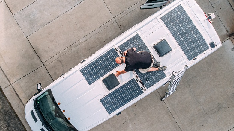 Person cleaning flexible solar panels on roof
