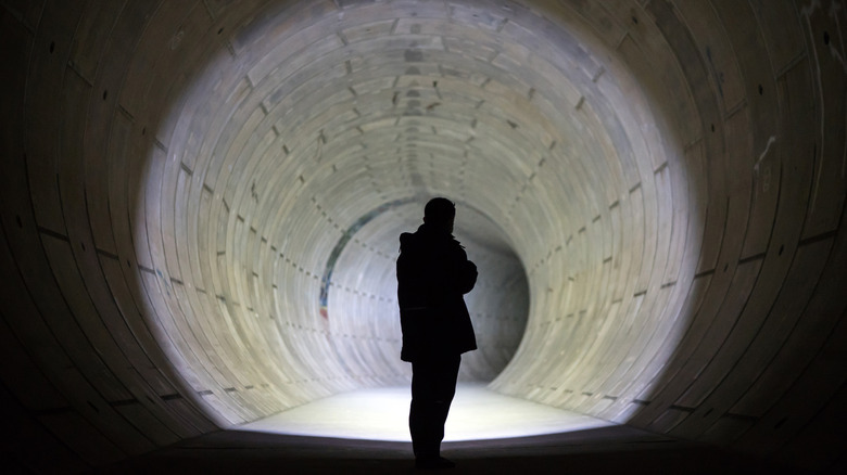 A person illuminating a tunnel with a flashlight.